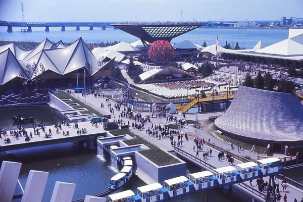 Pavillons de l' Ontario, du Canada, des Provinces-de-l'Ouest, vus depuis le pavillon de la France. À gauche , le bassin et les chutes d'eau du pavillon du Québec. On voit bien le Minirail ceinturant les sites des pavillons.